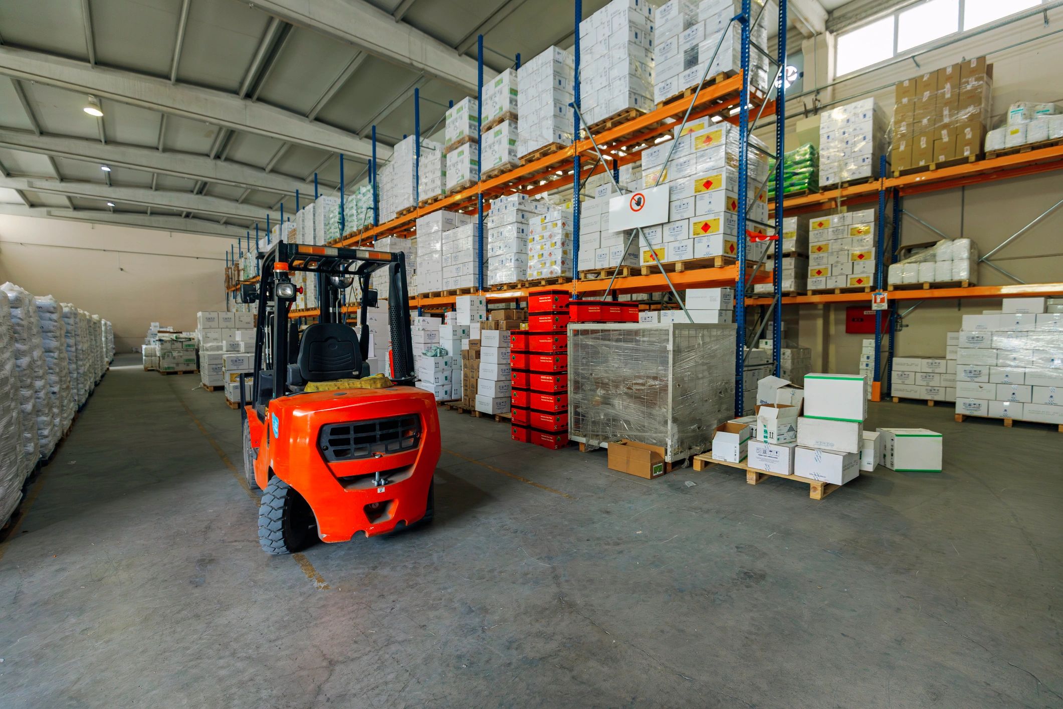 Forklift in a modern warehouse aisle with palletized goods